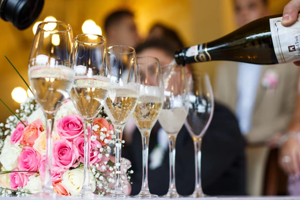 Taças de champagne sendo servidas em evento sofisticado, ideal para serem acompanhadas por uma champanheira de inox.